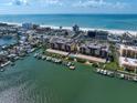 An aerial view of a luxury real estate development with water access, docks, and ocean views near a sandy beach at 5301 Gulf Blvd # C202, St Pete Beach, FL 33706