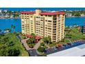 A waterfront condo building with tropical landscaping, a parking lot, and beautiful ocean views at 700 Island Way # 404, Clearwater Beach, FL 33767