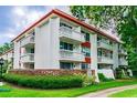 Low angle view of condo building showing balcony views, red trimming, and meticulous landscaping at 2630 Pearce Dr # 107, Clearwater, FL 33764