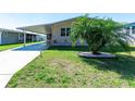 Well-manicured front lawn featuring a lovely palm tree and a paved driveway with a covered carport at 36838 Tara Ave, Zephyrhills, FL 33542