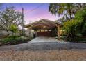 Stone façade garage featuring a stylish wooden carport with detailed landscaping at 680 George S St, Tarpon Springs, FL 34688