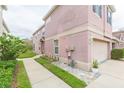 Side view of a pink townhome featuring a walkway, landscaping, and access to the backyard at 10011 Tranquility Way, Tampa, FL 33625
