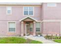 Front exterior view of a pink townhome with decorative door, manicured lawn, and neutral trim at 10011 Tranquility Way, Tampa, FL 33625