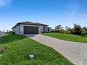 A modern one-story home with a two-car garage, set on a large lot with a paved driveway and green lawn at 14207 Fort Worth Cir, Port Charlotte, FL 33981