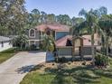 A beautiful two-story home features mature landscaping, a brick facade, and an expansive driveway at 2075 Warwick Dr, Oldsmar, FL 34677