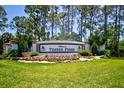 Welcoming Timber Pines community entrance with lush landscaping, flowers, and mature trees at 2348 Rolling View Dr, Spring Hill, FL 34606