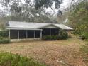 Back exterior of home with a screened in porch addition surrounded by mature trees and foliage at 3136 Hurley Rd, Valrico, FL 33596