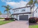 Beautiful two-story home featuring a paver driveway, a two car garage, and tropical landscaping at 4302 W San Pedro St, Tampa, FL 33629