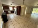 Open kitchen with dark wood cabinets, stainless steel appliances, tile flooring, connecting to the rest of the home at 7425 Riverbank Dr, New Port Richey, FL 34655