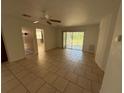 An empty living room with tile flooring, neutral paint, a ceiling fan and a large sliding door opening to the backyard at 7425 Riverbank Dr, New Port Richey, FL 34655