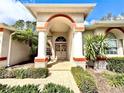 Close-up of a home's front entrance showcasing brick pavers, decorative wreath and well-maintained landscaping at 9006 Callaway Dr, Trinity, FL 34655