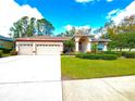 Charming single-story home featuring a three-car garage, landscaped lawn and red-trim accents at 9006 Callaway Dr, Trinity, FL 34655