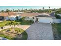 Beautiful single-story home featuring a brick driveway, lush landscaping, and an attached two-car garage at 102 23Rd St, Belleair Beach, FL 33786