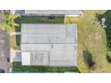 Aerial view of a home with a metal roof, driveway, and surrounding greenery at 37042 Lois Ave, Zephyrhills, FL 33542