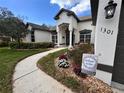 Beautiful home exterior with a well-maintained lawn, flowering plants, and a welcoming walkway at 1301 Jen Ma Jo Ln, Lutz, FL 33549