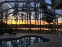 Screened-in pool area overlooking a tranquil lake and sunset with a brick deck and comfortable lounge seating at 1301 Jen Ma Jo Ln, Lutz, FL 33549