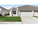 Home with a two car garage, a neatly maintained lawn, and an arched window at 1847 Ravenridge St, Wesley Chapel, FL 33543