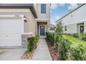 View of the front entry with a concrete walkway, well maintained landscaping, and a one car garage at 21404 Darter Rd, Land O Lakes, FL 34638