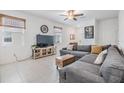 Living room with tile floors, a gray sofa, a ceiling fan, and a wall mounted TV at 21404 Darter Rd, Land O Lakes, FL 34638