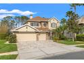 Beautiful two-story home with a three-car garage, stone accents, and a well-manicured front lawn at 23425 Vistamar Ct, Land O Lakes, FL 34639