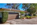 Attractive single-story home with a brown garage door, mature trees, and a beautifully landscaped front yard at 4100 Narvarez S Way, St Petersburg, FL 33712