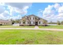 Charming two-story home with black shutters, a walkway, mature trees, and a lush green lawn at 4411 Miley Rd, Plant City, FL 33565