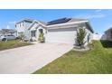 A well-maintained home featuring a two-car garage, solar panels, and a lush green lawn at 1014 Coastal Hammock Ave, Ruskin, FL 33570