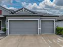 A three-car garage with gray doors and white trim, offering ample space for vehicles and storage at 12811 Wheatgrass Ct, Parrish, FL 34219