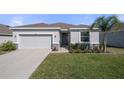 Beautiful single-story home with a manicured lawn, light grey garage door, and stone veneer accents at 13359 Golden Lime Ave, Spring Hill, FL 34609