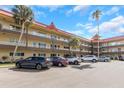 Exterior building view showcasing mature palm trees, red roofing and covered walkways at 2403 Finlandia Ln # 27, Clearwater, FL 33763