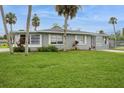A gray single-story home surrounded by a lush green lawn and accented with vibrant tropical landscaping at 112 Rose St, Venice, FL 34293
