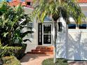 Home's front entrance with tropical landscaping, brick steps, and an updated storm door at 1616 Sand Key Estates Ct, Clearwater Beach, FL 33767