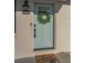 Close-up of a charming light blue front door with wreath, stylish hardware and welcome mat at 1633 Clearview Ave, Clearwater, FL 33756