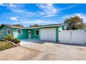 Side view of a cute green home showing the garage, manicured shrubbery, and a partial view of the back yard at 3543 Stokes Dr, Sarasota, FL 34232