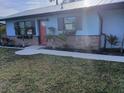 Charming home with a well-maintained lawn, garden beds, and a bright red front door at 402 Mary St, Punta Gorda, FL 33950
