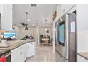 Open-concept kitchen with stainless steel refrigerator, granite counters, white cabinets, and view to living area at 1308 Syrah Dr, Oldsmar, FL 34677