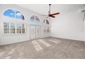 Bright living room with large arched windows and doors, ceiling fan, and neutral carpet at 14584 El Paseo Dr, Seminole, FL 33776