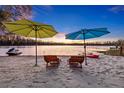 Beautiful sandy beach with seating, umbrellas, watercraft and lake at sunset create a relaxing outdoor living space at 19242 Blount Rd, Lutz, FL 33558