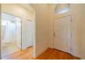 Bright foyer featuring wood floors, a white front door with transom window, and a glimpse into a bathroom at 2313 Nottingham Greens Dr # 2313, Sun City Center, FL 33573