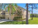 Attractive two-story townhome featuring a tan stucco exterior, lush landscaping, and attached garages at 2824 Conch Hollow Dr, Brandon, FL 33511
