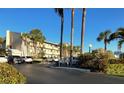 View of the condo complex from the parking area, highlighted by palm trees and manicured landscaping at 3400 Gulf Blvd # 304, Belleair Beach, FL 33786