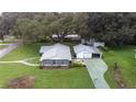 This aerial shot showcases a well-maintained home with a detached garage and expansive green lawn at 38055 Avion Dr, Zephyrhills, FL 33542