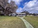 Inviting home featuring a well-manicured lawn and quaint walkway under a partly cloudy sky at 38055 Avion Dr, Zephyrhills, FL 33542
