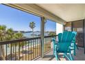 Inviting balcony with blue Adirondack chairs overlooking waterfront and swaying palm trees at 9525 Blind Pass Rd # 301, St Pete Beach, FL 33706
