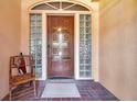 Inviting front door with glass brick sidelights, featuring an arched window above and a decorative carved wooden door at 1008 Royal Birkdale Dr, Tarpon Springs, FL 34688