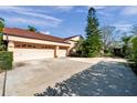 Spacious three-car garage with a large driveway and mature landscaping in a quiet neighborhood at 1008 Royal Birkdale Dr, Tarpon Springs, FL 34688