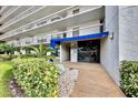 Building entrance with lush landscaping, brick walkway, and blue awning at 1324 Pasadena S Ave # 204, South Pasadena, FL 33707