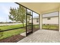 Covered and screened patio with brick floor overlooking the grassy backyard and community lake at 17541 Corkwood Bend Trl, Punta Gorda, FL 33982