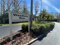 Entrance to Woodlake Run featuring an attractive community sign amidst lush landscaping at 233 Woodlake Wynde, Oldsmar, FL 34677