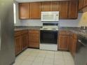 Charming kitchen featuring wood cabinetry, white appliances, and tiled flooring at 233 Woodlake Wynde, Oldsmar, FL 34677